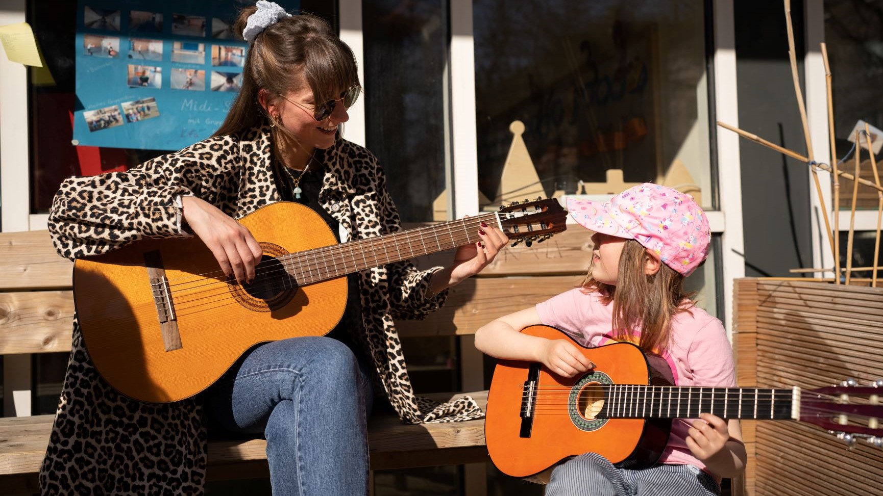 Pädagogische Fachkraft und Kind spielen zusammen Gitarre