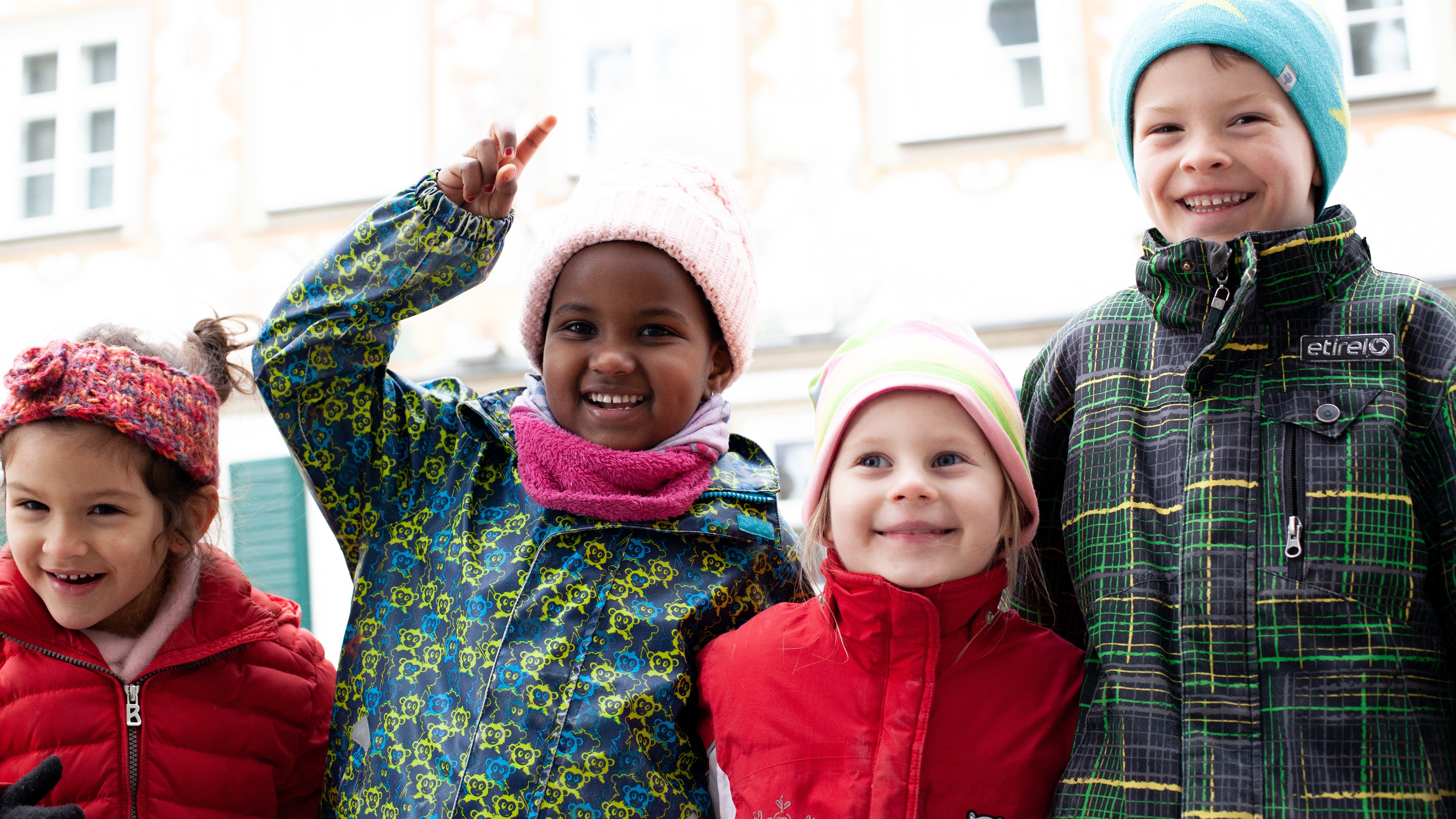 Vier Kinder sind draußen zur kalten Jahreszeit und lächeln