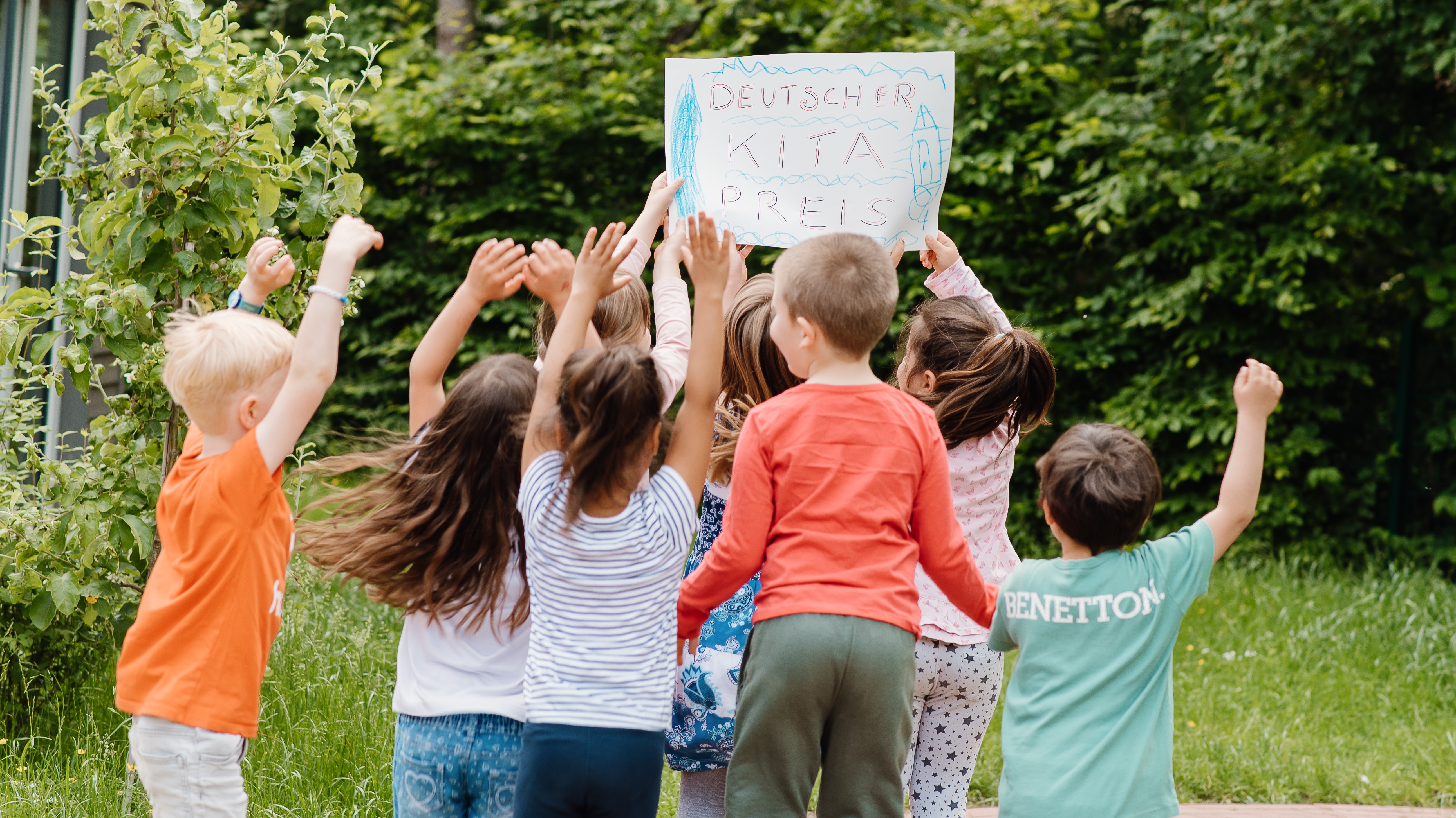 Kinder halten Schild vom Deutschen Kita-Preis hoch