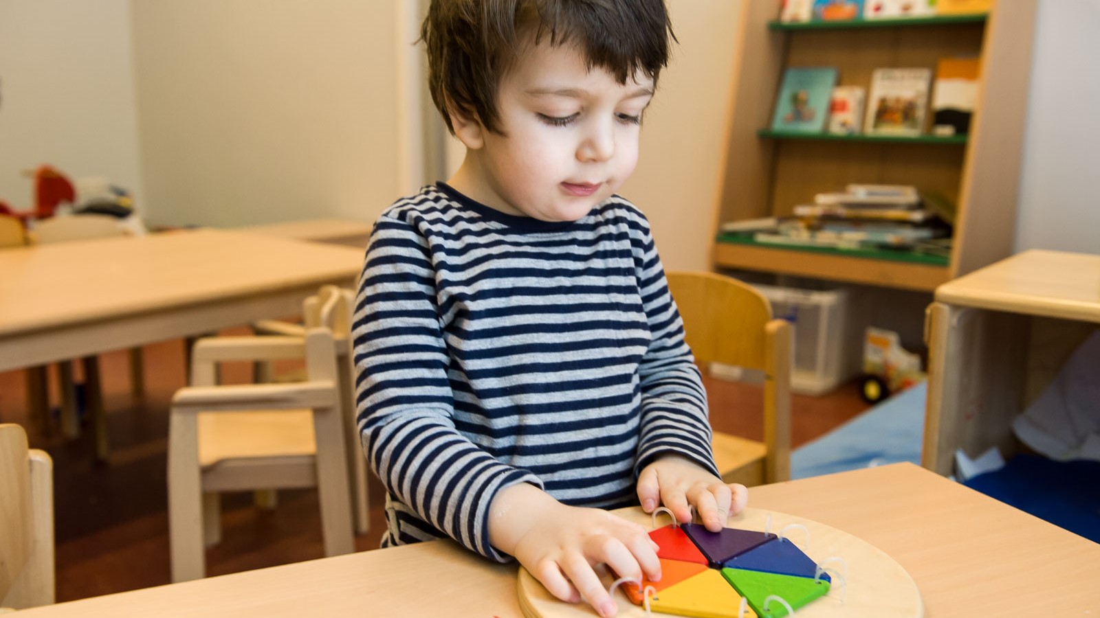 Ein Kita-Kind spielt mit einem geometrischen Holzpuzzle