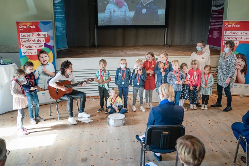 Kinder tragen Preisträger-Medaille und führen ein Musikstück auf