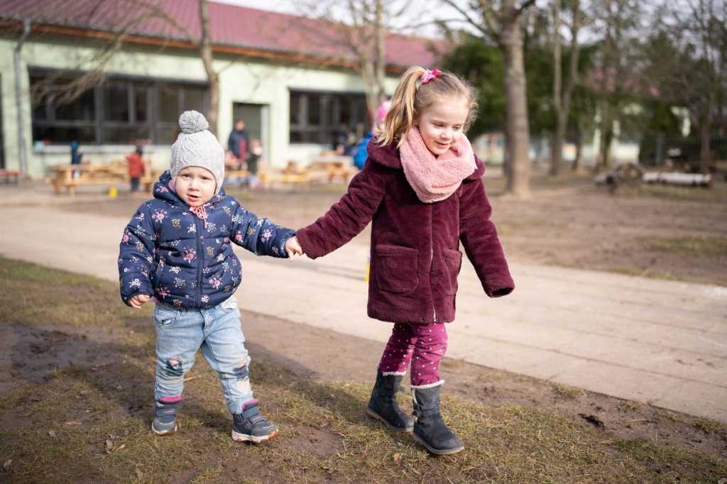 Ein Mädchen und ein Jungen halten sich an der Hand fest und laufen zusammen