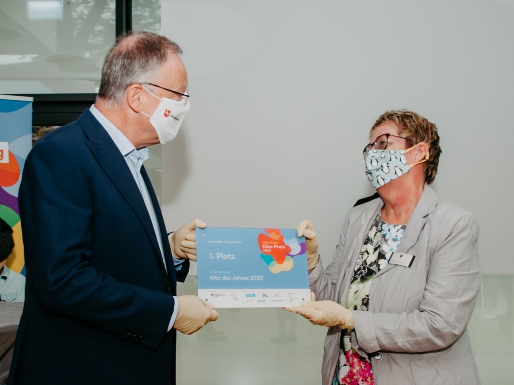 Ministerpräsident Stephan Weil überreicht Kita-Leiterin Doris Gießenberg die Preisträger-Plakette