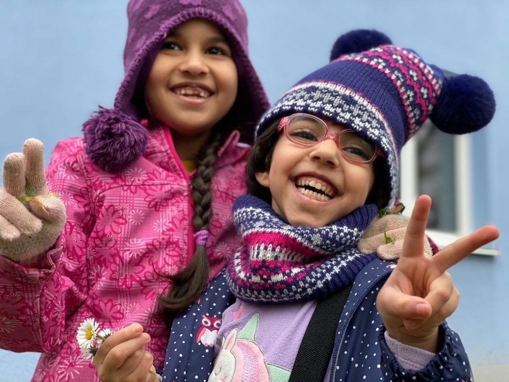 Zwei lachende Mädchen zeigen Peace-Zeichen