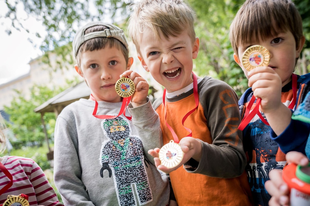 Drei Kinder der Kita Menschenskinder zeigen stolz ihre Medaillen