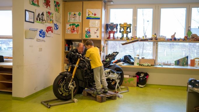 Kind und Fachkraft reparieren Motorrad