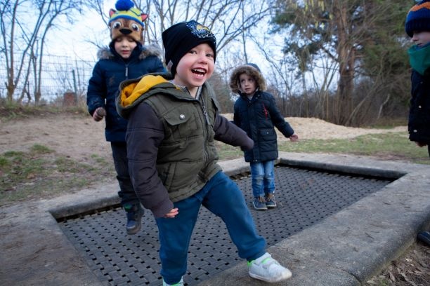 Drei Kinder springen lachend auf einem Trampolin