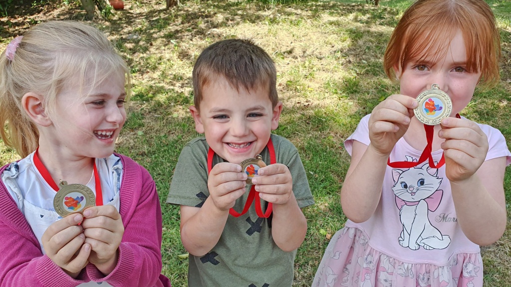 drei Kinder präsentieren ihre Medaillen